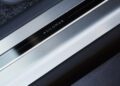 Close-up of a metallic car door sill with "ASILOMAR" engraved on a black strip, featured on the exclusive Range Rover SV Asilomar and showcased during Monterey Car Week, surrounded by textured and smooth surfaces.