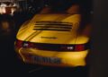 Rear view of a yellow Porsche Speedster with license plate "AE 911 SH," parked in a dimly lit space, capturing the spirit of Sonderwunsch customization.