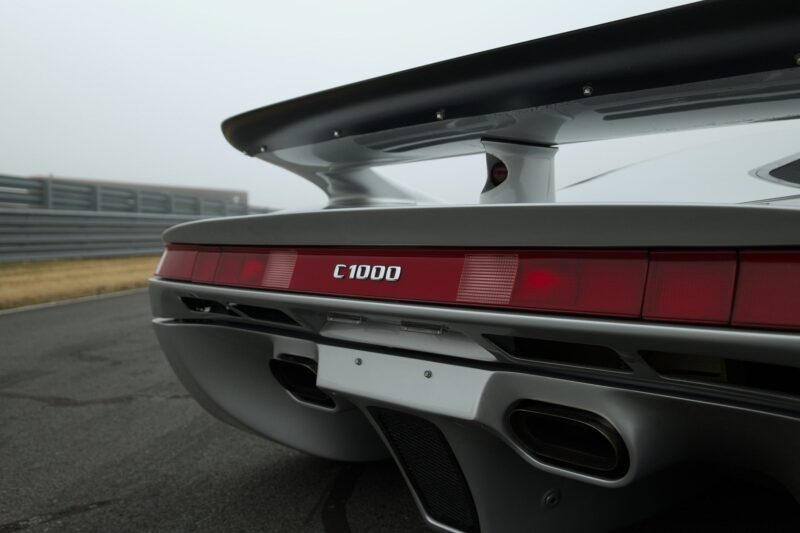 Close-up of the rear end of the Lotec C1000, showcasing its taillights, spoiler, and exhaust on a racetrack—perfect for a Film Friday feature on Petrolicious.