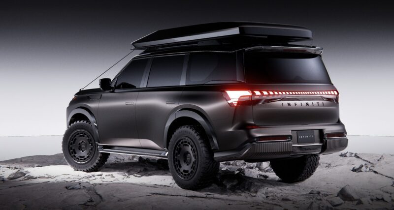 Matte black SUV with off-road tires, a roof box, and distinctive rear LED lights is parked on rocky terrain under overcast lighting, reminiscent of the bold styling seen at Infiniti’s 2025 Monterey Showcase: QX80 and QX65 SUV Concepts Take Center Stage.