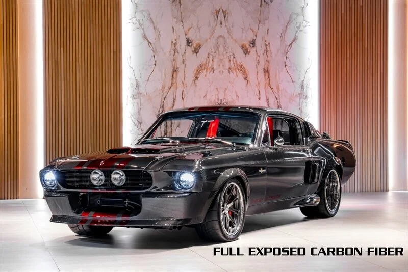 A black custom classic muscle car with red accents and exposed carbon fiber is displayed indoors, set against marble and wood panel backdrops. Text reads "FULL EXPOSED CARBON FIBER.