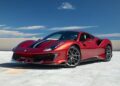 A track-ready Ferrari 488 Pista with black racing stripes is parked on a rooftop under a clear blue sky.