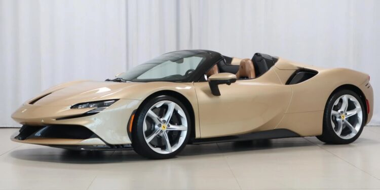 A beige Ferrari convertible sports car with a sleek design, silver rims, and a black retractable roof is parked indoors against a white background—showcasing one of the exclusive Ferrari colors for sale.