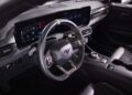 The image shows the interior of a modern Ford Mustang, similar to the First Drive: Six-figure Ford Mustang GTD Boasts Peak Pony Muscle, featuring a digital instrument panel, multifunction steering wheel, and rotary gear selector.