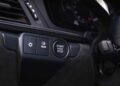 Close-up of a car dashboard in the 2025 Porsche 911 Carrera GTS T-Hybrid, featuring buttons for automatic headlights, rear defroster, and a start/stop engine button as part of its electrifying performance upgrades.