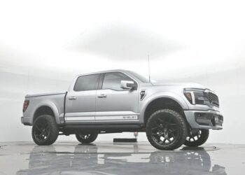 A silver Ford F-150 pickup truck with large black wheels and bold "SHELBY" branding is parked in a white studio setting, showcasing the premium style of Shelby trucks.