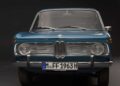 Front view of a classic blue BMW car with round headlights, chrome grille, and a German license plate "M FF 1963 H" against a dark background—an icon preceding innovations like the BMW iX3, which launches the Neue Klasse era with 400-mile range and 463 HP.