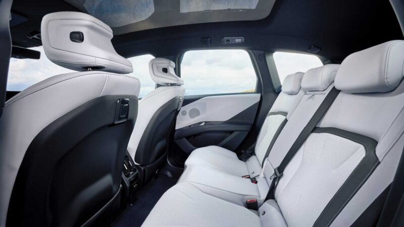The image shows the rear seats of a modern car with light-colored upholstery, headrests, and large windows allowing natural light inside—highlighting the premium comfort you'd expect from a BMW iX3, which launches the Neue Klasse Era with 400-mile range and 463 HP.
