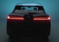 Rear view of a dark blue BMW iX3 with illuminated red taillights, photographed against a blue gradient background, symbolizing how the BMW iX3 launches the Neue Klasse era with its impressive 400-mile range and 463 HP.