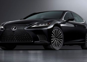 A black Lexus sedan is parked in a studio setting with a gray gradient background, viewed from a front side angle.