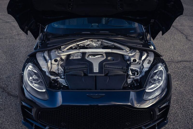 A 2026 Aston Martin DBX S First Drive: The Best Super SUV Gets Even Better, with its hood open, shows a clean and detailed view of the engine bay and front headlights on a paved surface.