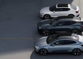 Three modern cars, two sedans and one SUV, are parked side by side on a clean, gray pavement under partial sunlight.