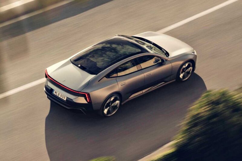 A silver Polestar 5, the brand’s first true flagship EV GT debuting at IAA 2025, drives on a paved road, viewed from above and behind.