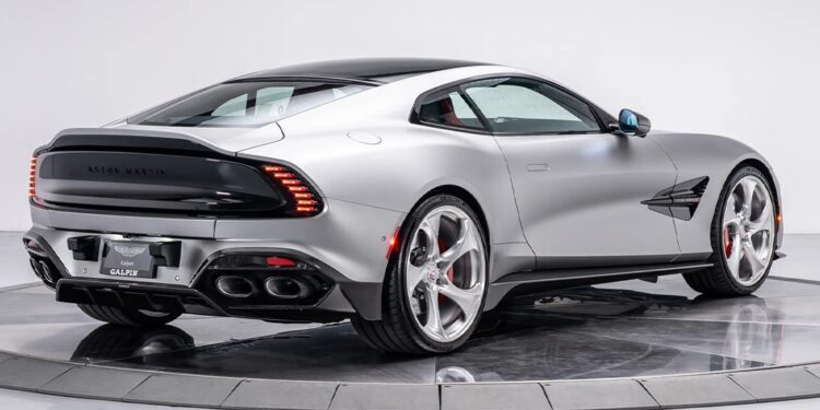A silver Aston Martin coupe from Galpin Aston Martin is displayed on a rotating platform, viewed from the rear three-quarter angle in a studio setting—an exquisite choice among exotics for sale.