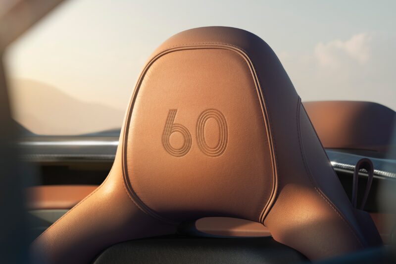 Close-up of a brown leather car seat headrest with the number "60" embossed on it, celebrating Q by Aston Martin Marks 60 Years of Volante With Ultra-Exclusive Anniversary Editions, set against a blurred background.