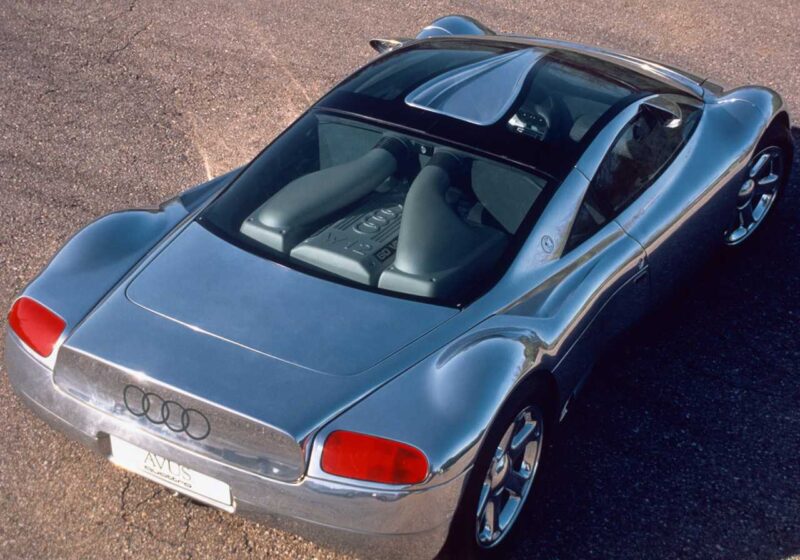 A silver Audi electric car, possibly the Audi TT successor or a future flagship EV, is parked on a paved surface, viewed from above at an angle, showcasing its rear engine and aerodynamic design.