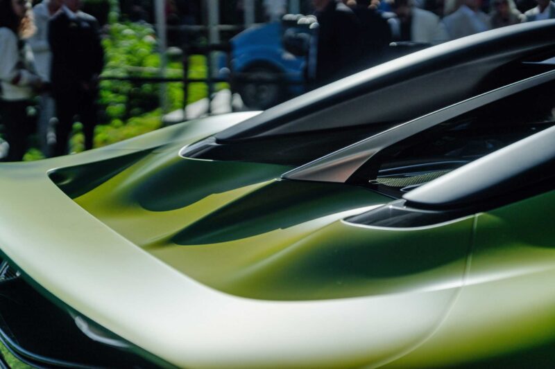 Close-up of the rear section of a green 1-of-1 Bugatti Brouillard with aerodynamic vents, photographed outdoors during its European debut at Wheels Mariënwaerdt, with people and another vehicle visible in the background.