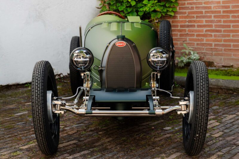 Front view of the 1-of-1 Bugatti Brouillard making its European debut at Wheels Mariënwaerdt, parked on a cobblestone surface and showcasing its vintage green paint, headlights, grille, and front wheels.