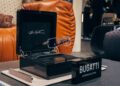 A pair of luxury Bugatti eyeglasses, inspired by Tourbillon design, displayed in an open black case with a "Bugatti Eyewear Collection" sign on the table—perfect for SILMO 2025.