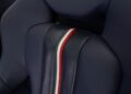 Close-up of a dark blue perforated car seat with a stripe in red, white, and green running vertically down the center—an interior detail from the ultra-rare Ferrari 458 Speciale Aperta.