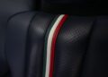 Close-up of a dark perforated leather car seat with a vertical stripe in green, white, and red stitching down the center, as seen in the stunning 2015 Ferrari 458 Speciale Aperta.