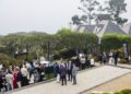 A group of people in formal and semi-formal attire gather outdoors on a lawn near a house, with a Bugatti Broward banner in the background, celebrating Abraham Cohen as Best Performing Brand Manager.