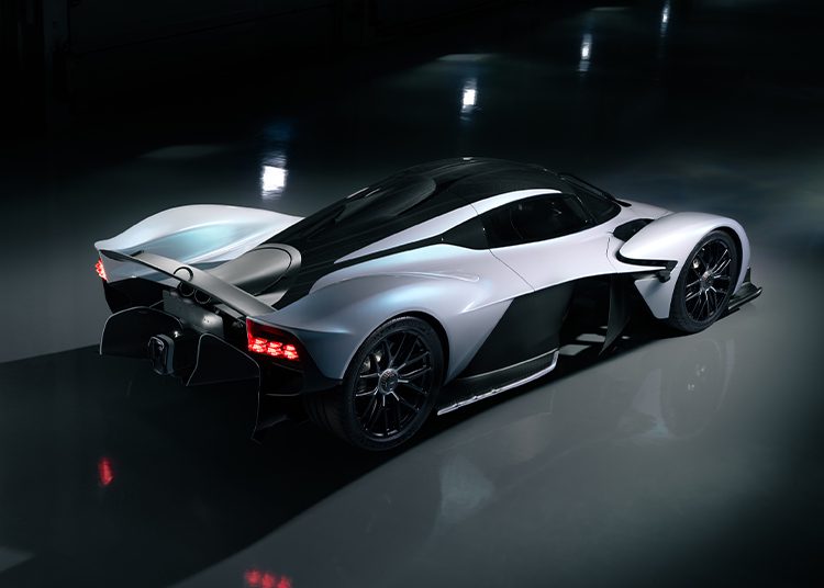 A sleek, black and white sports car with aerodynamic curves and exposed rear wheels, photographed indoors under soft lighting—perfect for a Broad Arrow Auction or reminiscent of the striking Aston Martin Valkyrie design.