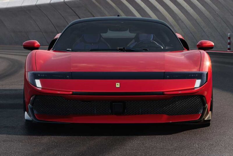 A red Ferrari sports car, possibly the Ferrari SF90 Stradale, is shown from the front, parked on a racetrack with curved barriers and a striped pattern—perfect for a Comparison: Ferrari SF90 Stradale Vs. Ferrari 849 Testarossa.