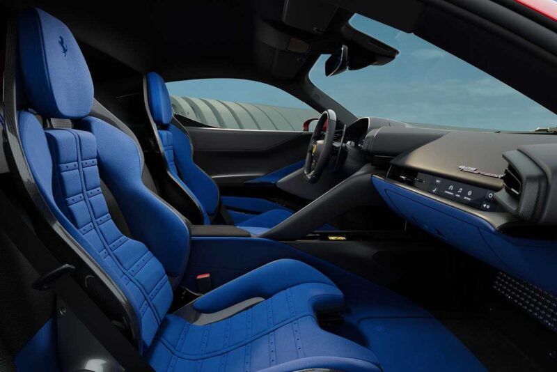 Interior view of a sports car featuring blue bucket seats, a modern dashboard, and a digital display, with sunlight illuminating the cabin—perfect for those interested in the Comparison: Ferrari SF90 Stradale Vs. Ferrari 849 Testarossa.