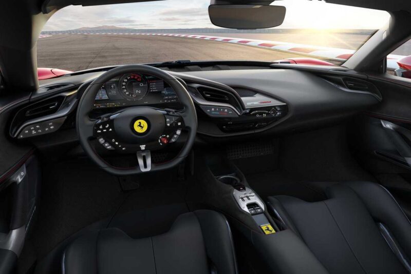 The interior of a modern Ferrari sports car, such as in the Comparison: Ferrari SF90 Stradale Vs. Ferrari 849 Testarossa, showcases a sleek steering wheel, advanced digital displays, and dashboard, with a racetrack visible outside the windshield.