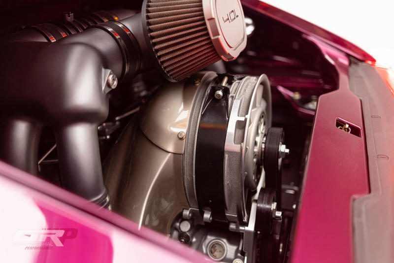 Close-up view of a car’s engine compartment featuring a 4.0L air-cooled engine with visible intake filter and pulleys, set in a glossy magenta Gunther Werks Speedster.