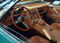 Vintage car interior with tan leather seats, wooden steering wheel, manual gear shift, and classic dashboard featuring analog gauges and control switches inspired by Lamborghini Polo Storico heritage.
