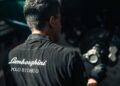 A person in a "Lamborghini Polo Storico" shirt works near a brake disc, reflecting the passion for Lamborghini heritage and restoration in a workshop setting.
