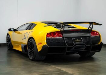 A yellow Lamborghini Murciélago SV sports car is parked indoors, viewed from the rear left angle with a large wing and black accents—an icon among exclusive Lamborghinis. Discover more at Lamborghini Montreal.