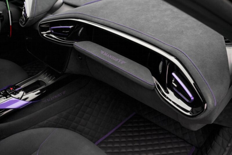 Close-up of a luxury car interior featuring black suede upholstery with purple accents and Mansory branding on the glove compartment, inspired by the MANSORY Previews Ferrari 12Cilindri-based Equestre ahead of Monaco Yacht Show.