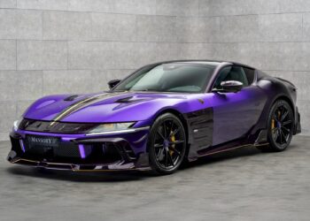 A purple MANSORY-modified sports car with black and gold accents, inspired by the Monaco Yacht Show, is parked indoors against a gray tiled wall.