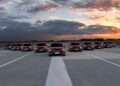 Nine red Mercedes-Benz cars are lined up side by side on an empty runway at sunset under a cloudy sky, showcasing the excitement Beyond the All-electric GLC: Mercedes-Benz at IAA 2025.