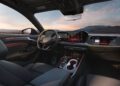Interior view of a modern 2026 Audi A6 featuring a digital dashboard, touchscreen displays, leather seats, and ambient lighting, with mountains visible through the windows. Discover luxury starting at a $64k price point.