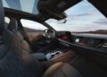 Interior of the 2026 Audi A6 featuring black leather seats, digital dashboard displays, and red accent lighting, viewed from the front passenger side with a clear sky visible through the windows.