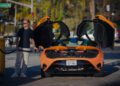 A person stands at a gas station refueling an orange McLaren with its butterfly doors open, preparing for a thrilling road trip that tests the States of Endurance.