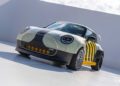 A customized compact car with a black, white, and yellow exterior, racing wheels, and aerodynamic modifications channels MINI’s Rally DNA Gets a Deus Makeover in Two Radical JCW Builds, parked on a smooth white surface.