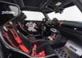 A stripped-down car interior featuring racing seats with red harnesses, minimal dashboard controls, a roll cage, and "DEUS" branding on the metal floor plate showcases how MINI’s Rally DNA gets a Deus makeover in two radical JCW builds.