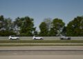 Three SUVs drive in a line on a track with trees in the background; the last vehicle, a new BMW iX5 Hydrogen, is partially camouflaged during series production testing.