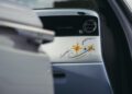 The interior of a Rolls-Royce Cullinan with the passenger door open reveals a dashboard featuring a hand-painted star and swirl design, complemented by the iconic Starlight Headliner.