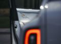 Close-up of a Rolls-Royce Cullinan with the rear door open, revealing a white interior panel featuring a blue and gold star design that evokes the cosmos. The red taillight is also visible in the foreground.