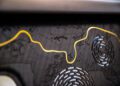 Close-up of a dark, embossed map labeled "Rayol-Canadel-sur-Mer" with a yellow, wavy line and circular, vent-like patterns.