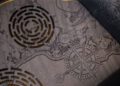 A close-up of an etched wooden map showcases intricate woodwork, featuring two circular maze designs and a detailed compass rose with cardinal directions.