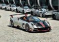 A silver and black sports car with red accents is parked on a cobblestone driveway, surrounded by similar cars—possibly stars like those Pagani will showcase at the upcoming 9th Historic Minardi Day in Imola.