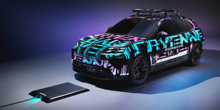 A Porsche electric SUV with glowing camouflage paint is parked next to a wireless charging pad on a studio set, previewing Porsche's plan to highlight wireless charging on the upcoming Cayenne Electric at IAA 2025. Purple and blue lighting enhances the scene.