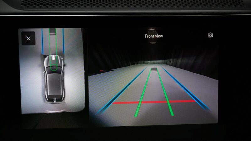 Digital display showing a car’s parking assist system with top-down and front camera views, guidance lines, and parking sensors—similar tech Porsche may highlight with wireless charging on the upcoming Cayenne Electric at IAA 2025.